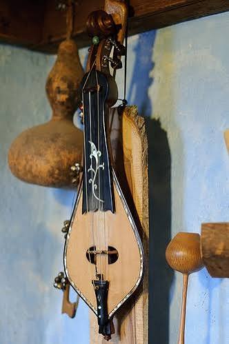 A stringed lyre hanging on a peg against a blue wall.