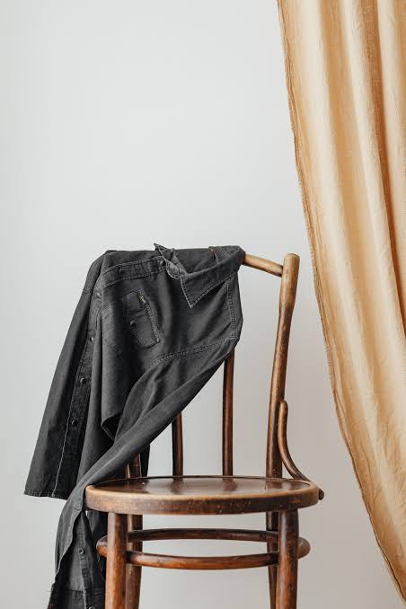A wooden chair with a cloak folded over its back.