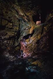 Near-black: the deep back wall of the cave they pressed themselves against.