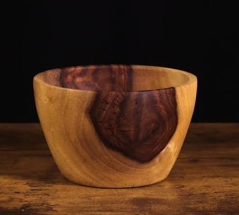 An empty wooden bowl on a dark table β the cup he poured the wine into, three times.
