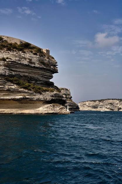 A cliff-walled harbour photographed from the water outside it β high headlands, calm water within.