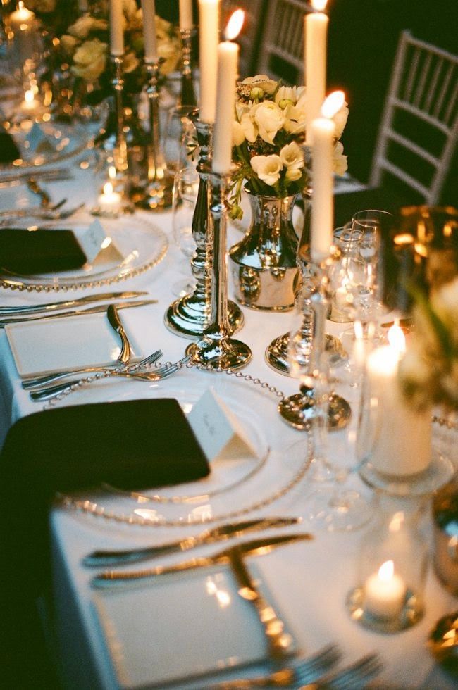 A long table laid for a great many people β candles, silver, white settings.